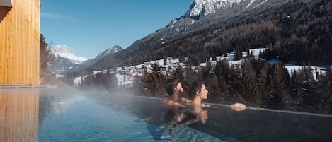 Una piscina cubierta, una piscina al aire libre, tumbonas