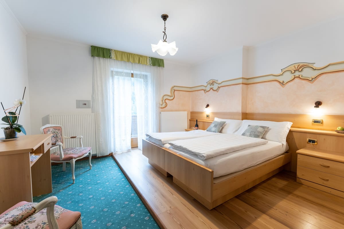 Una camera da letto con un letto di legno, due comodini, una scrivania e una sedia.