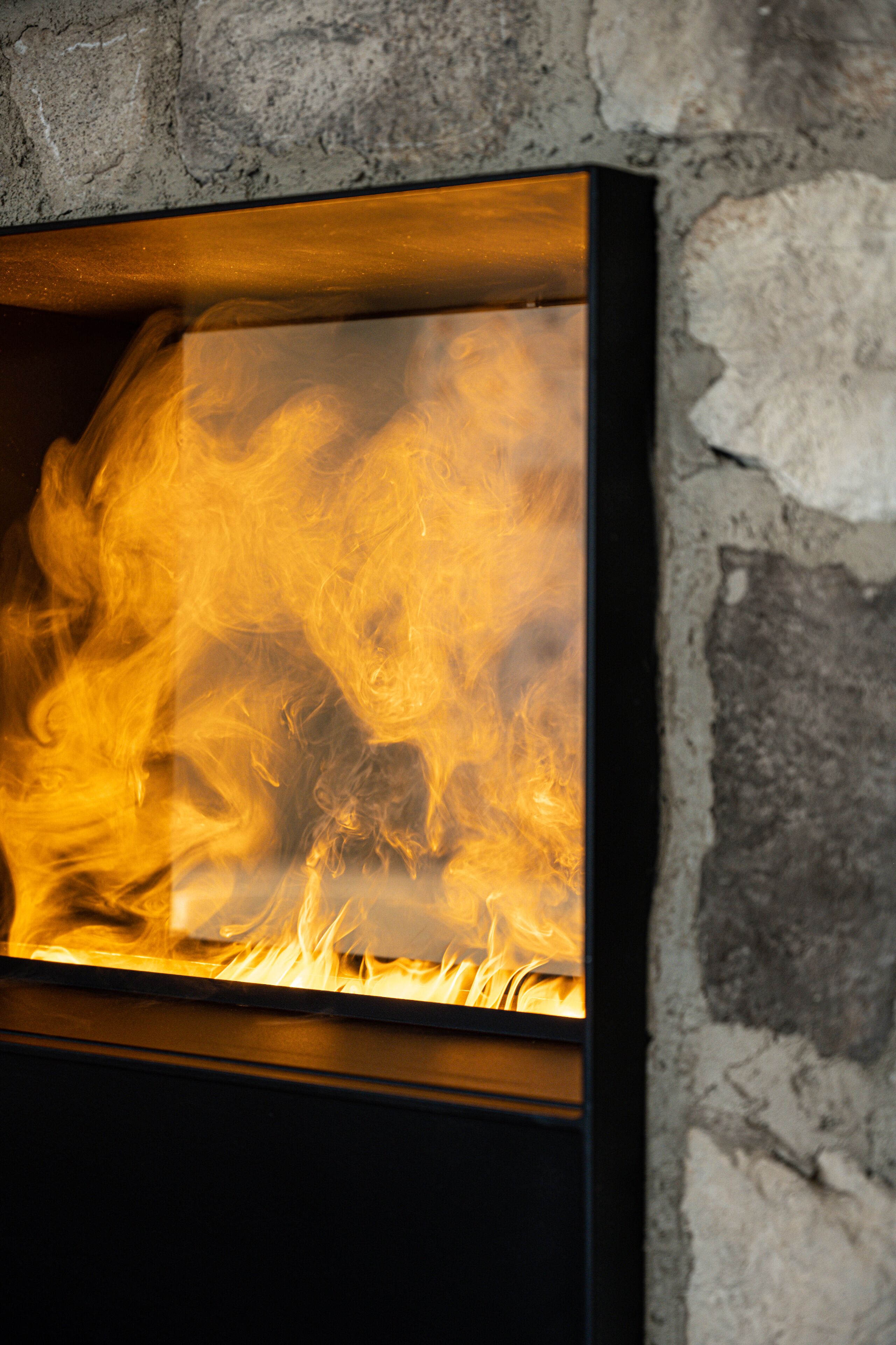 A fireplace with visible flames, set against a stone wall.