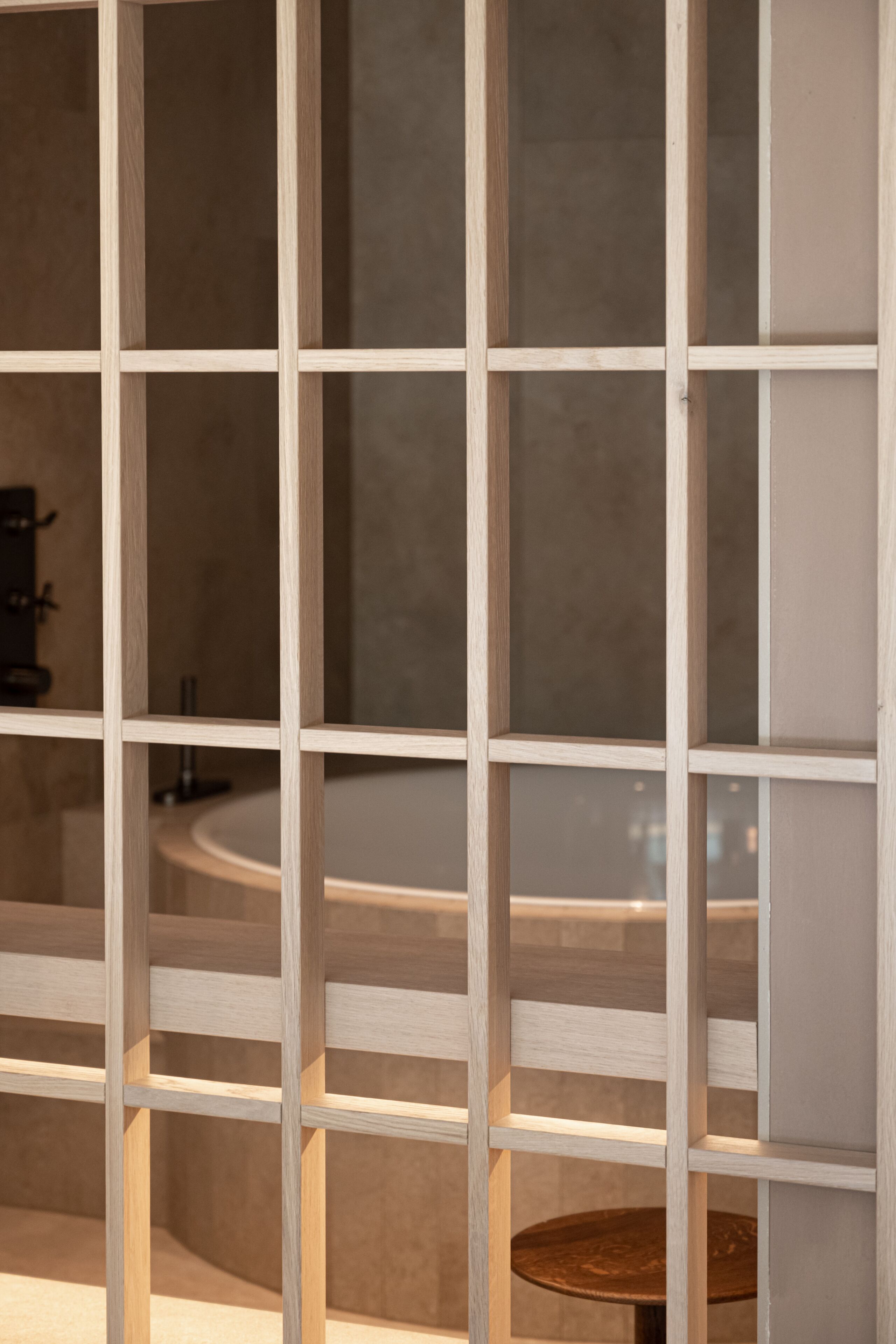 A wooden partition with a circular table and a sink in the background.