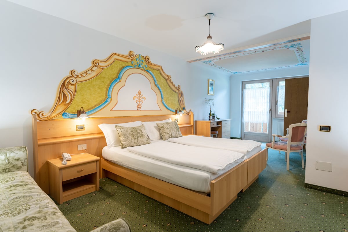 Una camera d'albergo con un letto grande, un comodino, una scrivania e una sedia.
