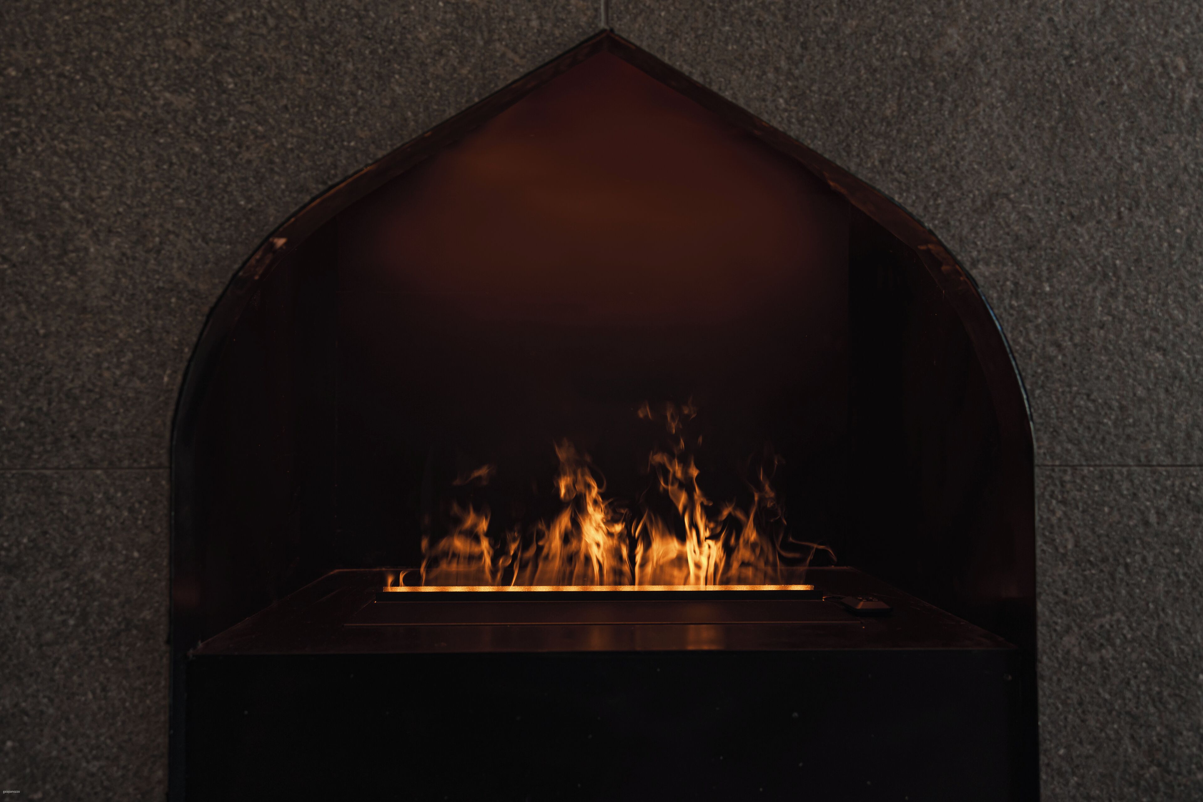 A fireplace with a dark, arched interior and visible flames.