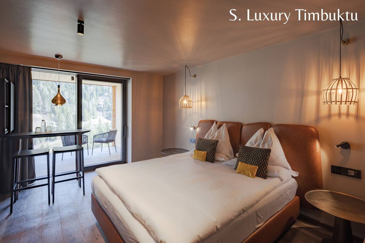 Una camera d'albergo moderna con un letto grande, una scrivania e un balcone vista all'esterno.