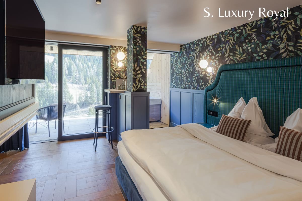 Una camera d'albergo moderna con un letto grande, una scrivania con una sedia, vista sull'esterno e una parete decorativa.