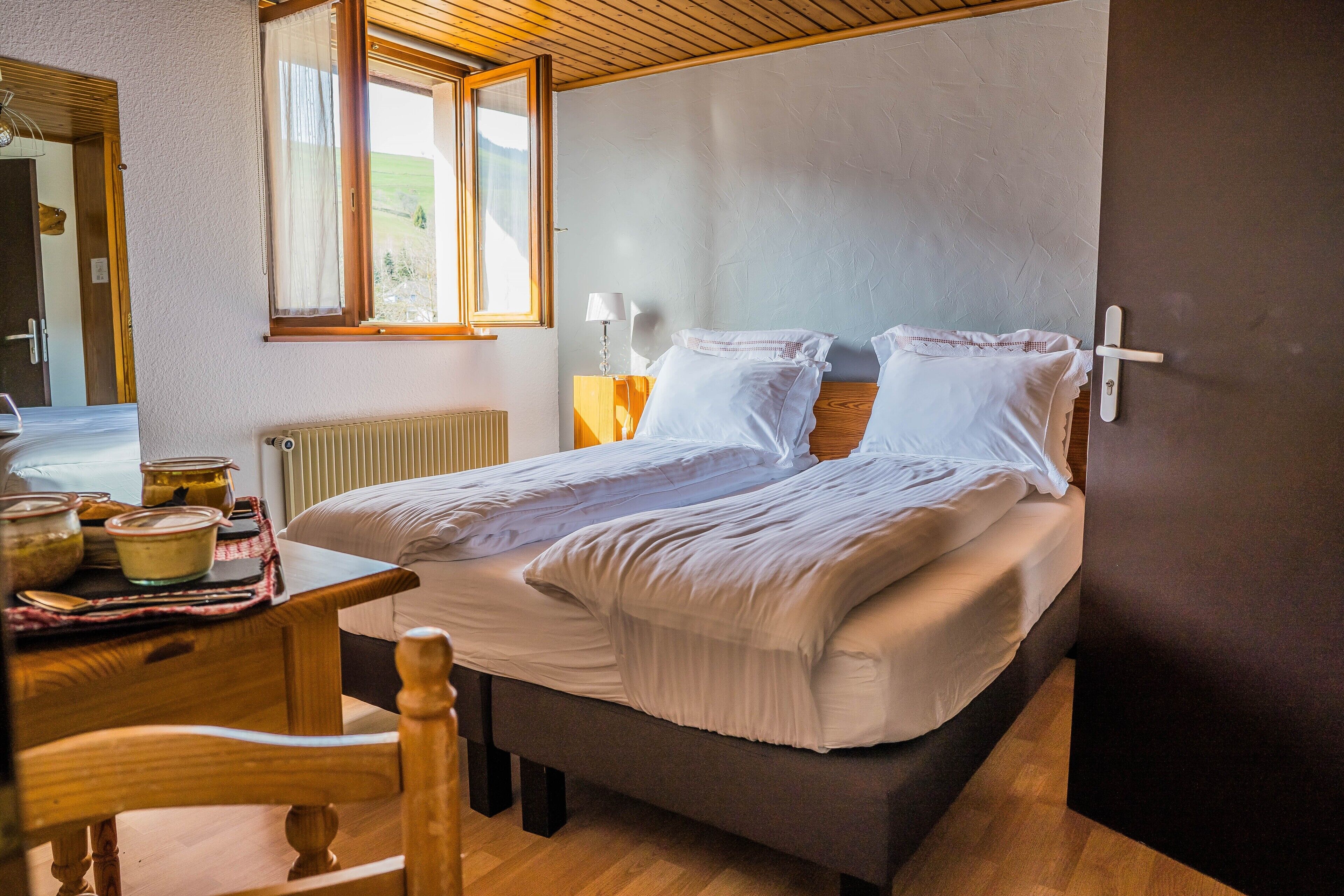 Een slaapkamer met een bed, nachtkastjes, een raam en een houten vloer.