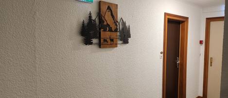 A hallway with a textured wall, a wooden decorative piece, and an exit sign.