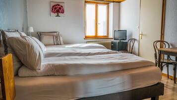 Une chambre à coucher avec un lit, une télévision, une chaise et une fenêtre.