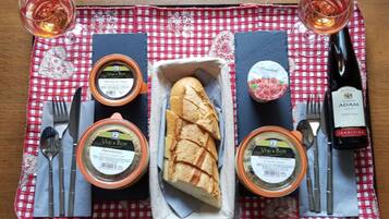 Uma mesa posta com uma baguete, dois potes de geleia Vi&Bon, uma garrafa de vinho Adam e uma toalha de mesa xadrez.