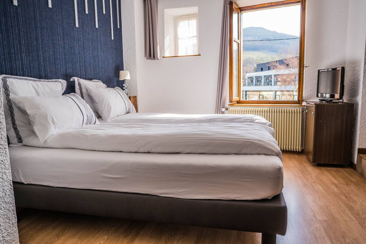 Un dormitorio moderno con una cama grande, un televisor y vistas al exterior.