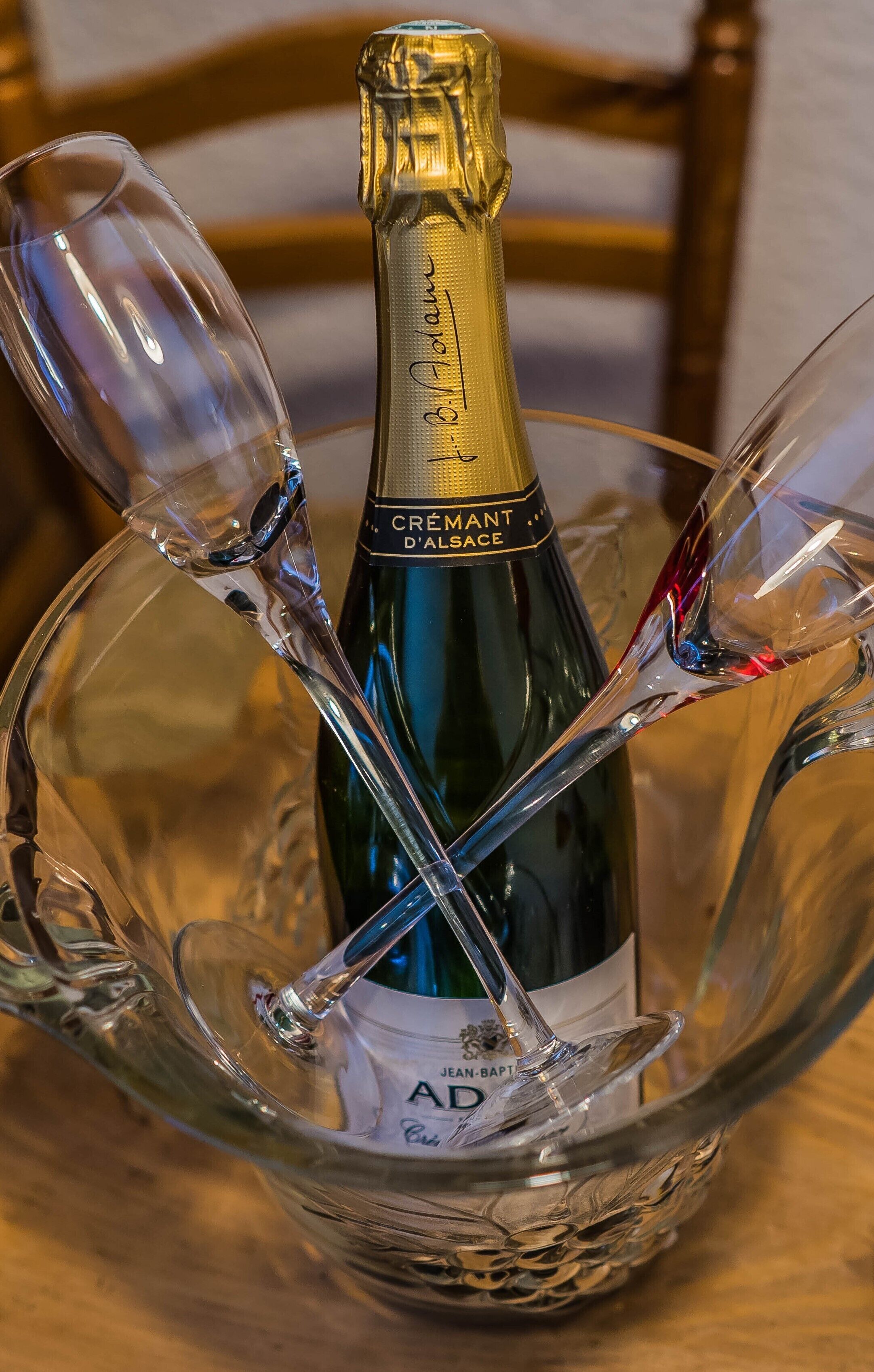Una botella de champán en un cuenco de vidrio con dos copas de vino.