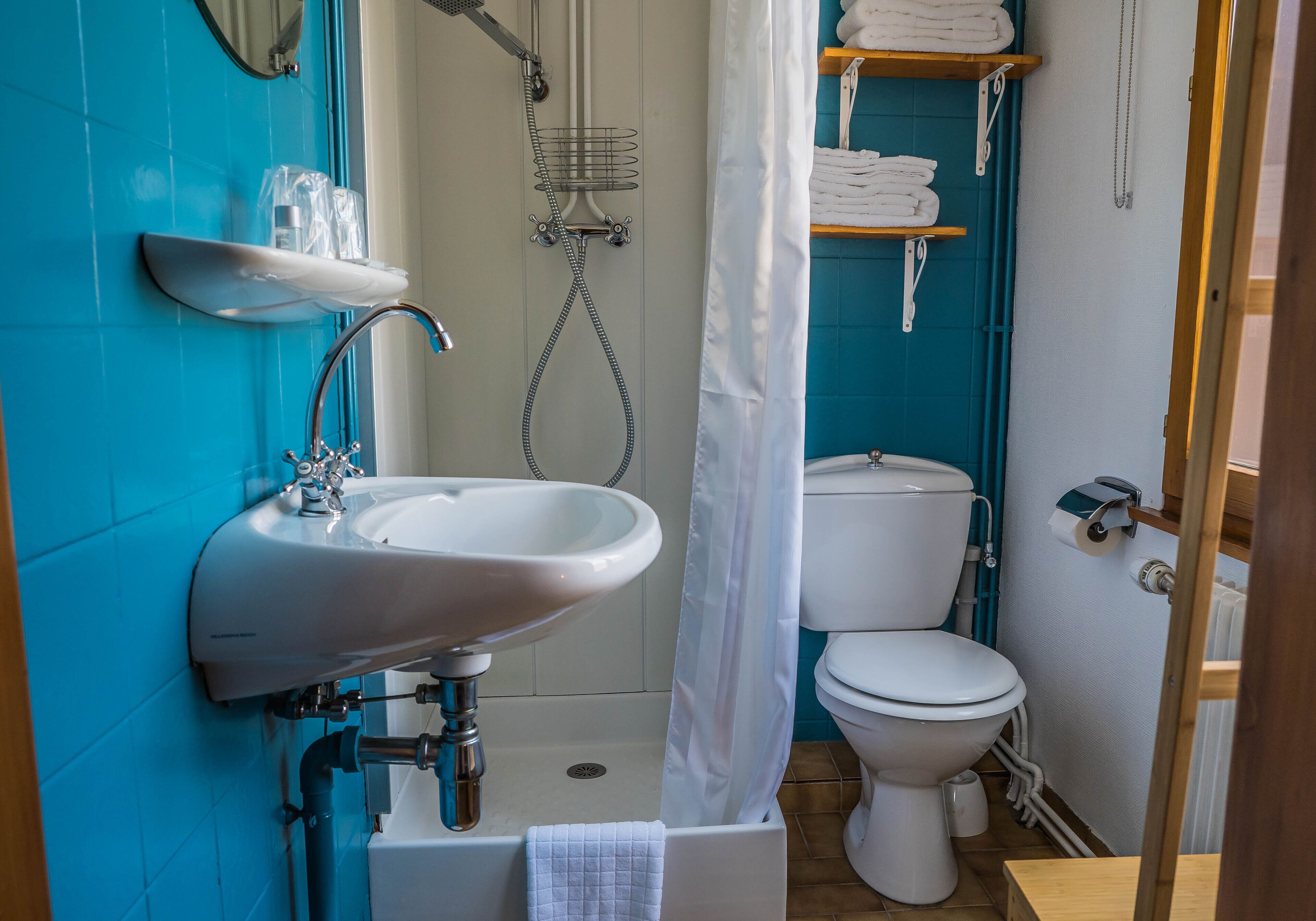 A bathroom with a sink, toilet, shower, and towel rack.