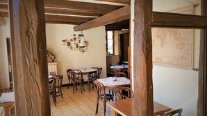 A rustic dining area with wooden beams, tiled flooring, and a chandelier. - Au Vieux Moulin (Lapoutroie)