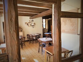 Uma zona de refeições rústica com vigas de madeira, soalho em azulejos e um candelabro.