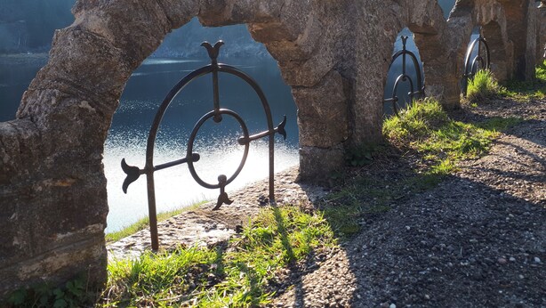 A stone archway with metal railings overlooking a body of water. - Au Vieux Moulin (Lapoutroie)