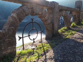 Arcada de pedra com grades de metal dando vista para um corpo d'água.