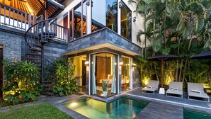 Una casa moderna con piscina, zona de estar exterior y exuberante vegetación.