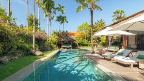 A swimming pool with lounge chairs and a gazebo in a tropical garden setting. - Villa Desa Roro Dua by Villa Finder (Canggu)