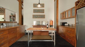 A modern kitchen with wooden cabinets, a stainless steel refrigerator, and a dining table. - Villa Desa Roro Dua by Villa Finder (Canggu)