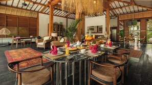 Un comedor espacioso con techo alto y luz natural, que cuenta con una isla central con artículos para el desayuno y asientos alrededor.