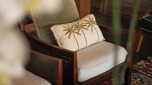 A wicker chair with a cushion and a palm tree embroidered pillow. - Villa Desa Roro Dua by Villa Finder (Canggu)