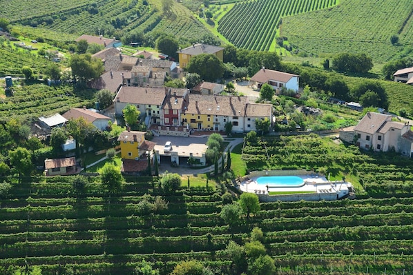 Une vue aérienne d’un vignoble avec des terrasses et une grande maison entourée de bâtiments plus petits.