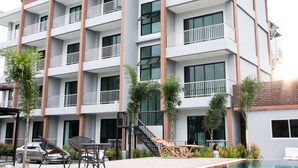 Un hotel de varios pisos con piscina, zona de estar al aire libre y una escalera que lleva a los pisos superiores.