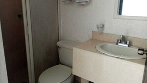 A small, compact bathroom with a toilet, sink, and a mirror above the sink. - Hotel Santander Inn & Suites (Ciudad Victoria)