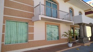 A two-story building with a balcony, large windows, and a potted plant. - Hotel Santander Inn & Suites (Ciudad Victoria)