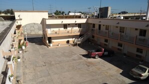 A multi-story building with a parking area, a staircase, and potted plants along the balconies. - Hotel Santander Inn & Suites (Ciudad Victoria)