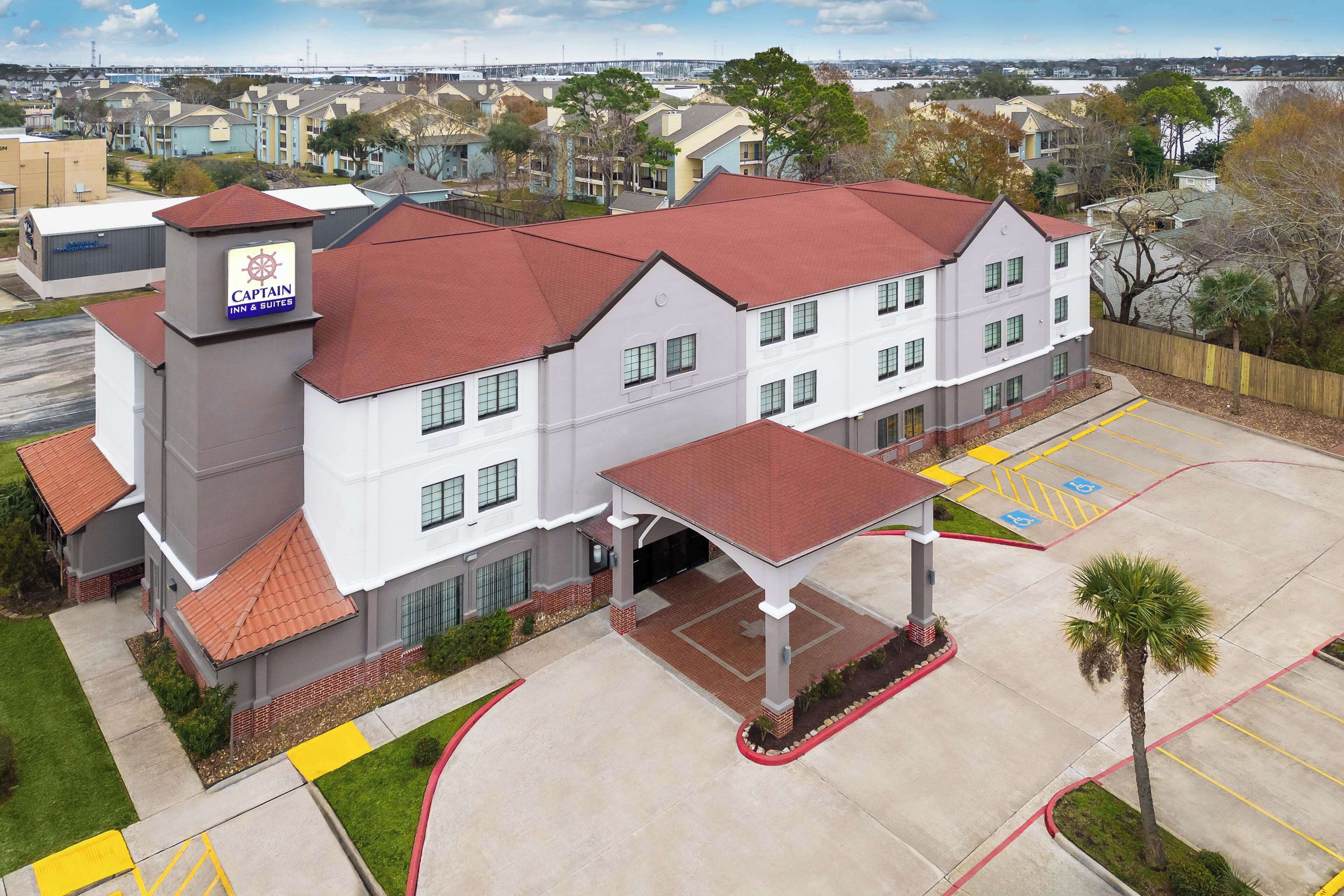 A hotel with a red roof, a sign reading "Captain Inn & Suites," and a parking lot with handicapped accessibility.