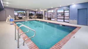 An indoor swimming pool with clear water, a diving board, and a lounge area with chairs and a table. - Melrose @ Seabrook, BW Signature Collection (Seabrook)