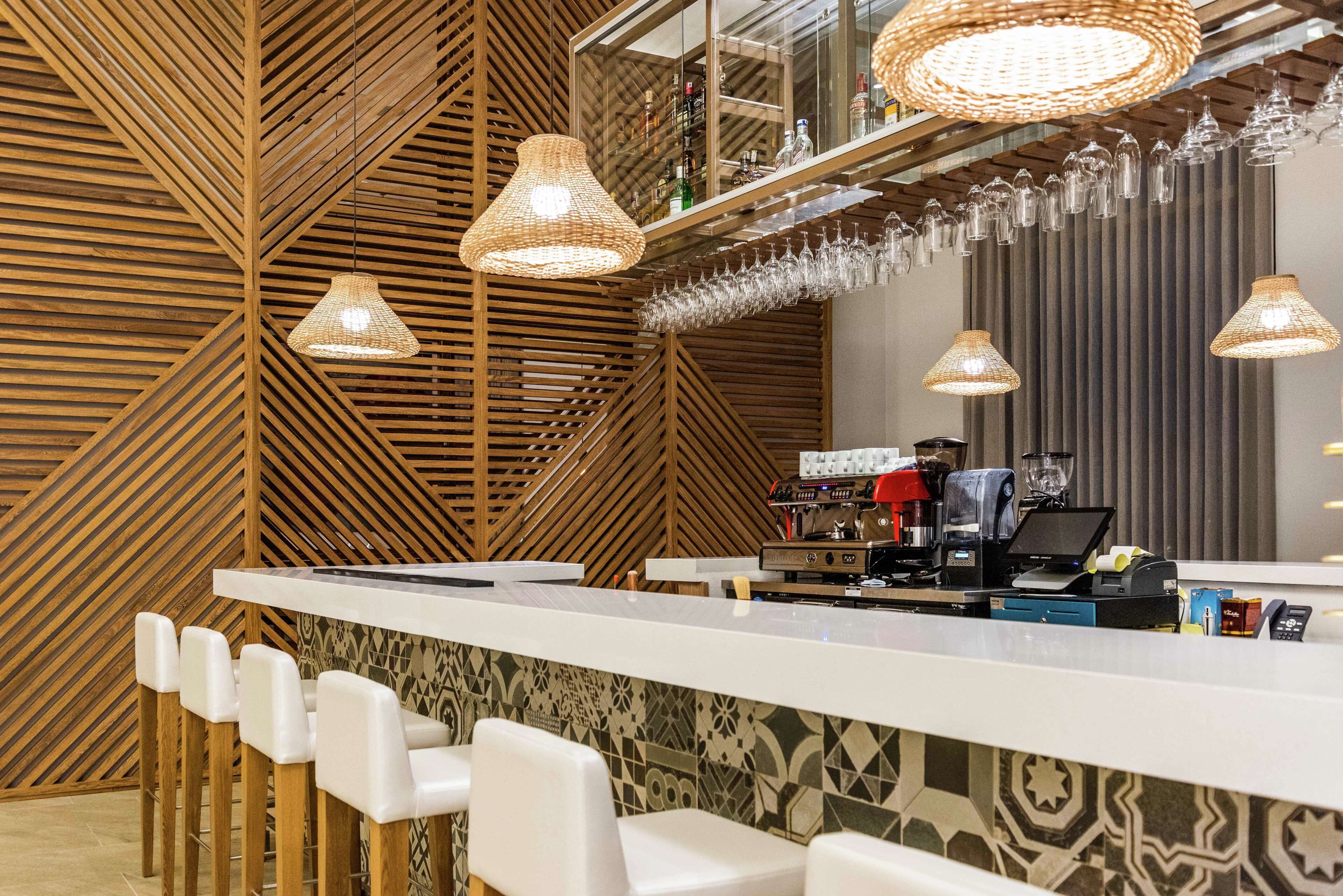 A bar area with a counter, bar stools, hanging lights, and a coffee machine.