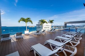A deck with sun loungers and palm trees overlooking the sea. - Hilton Garden Inn Santa Marta (Santa Marta)