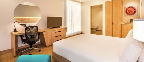 A modern hotel room with a large bed, a desk with a chair, a television, and a wardrobe.