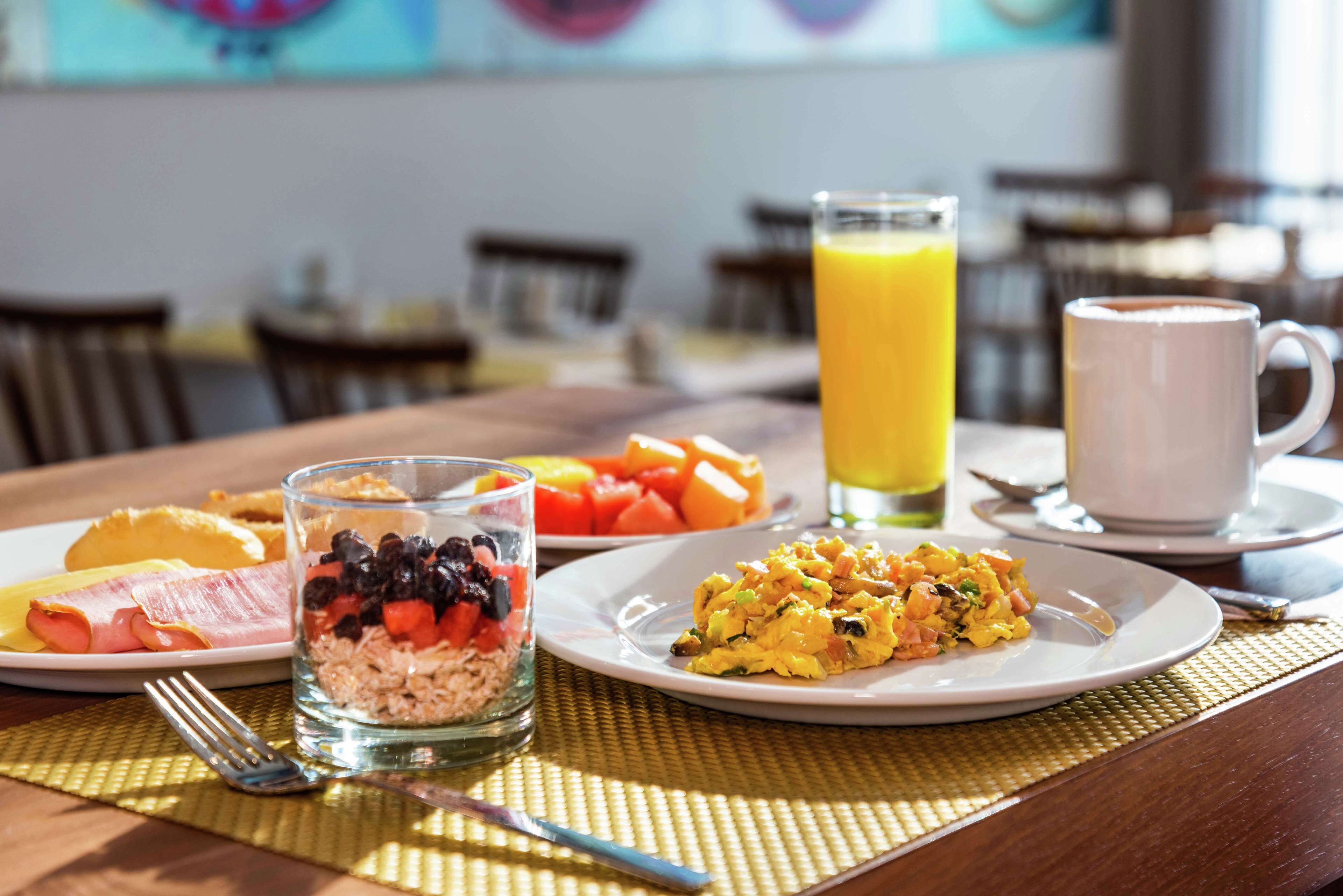 Un desayuno con platos de comida, un vaso de zumo de naranja y una taza de café.