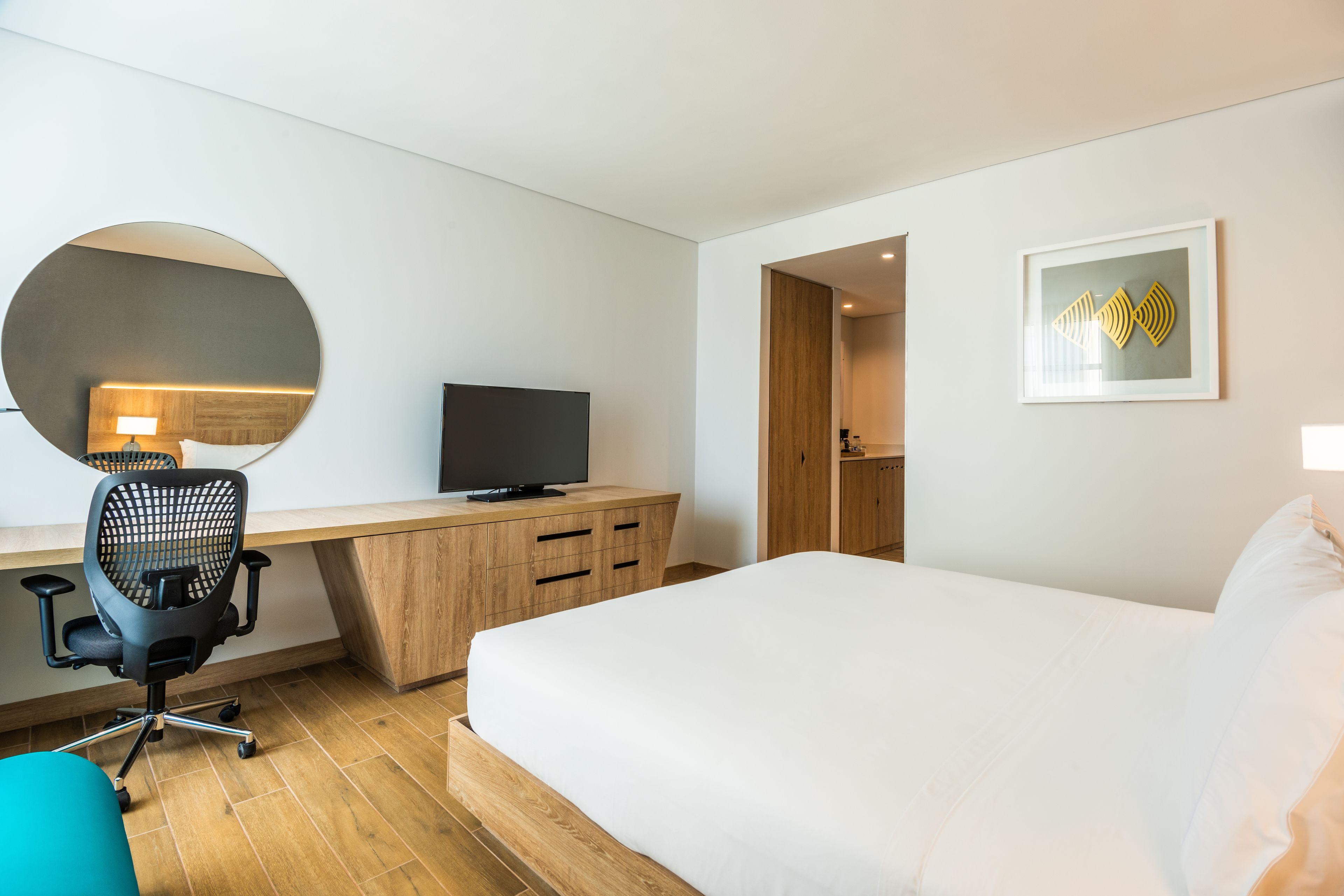 Une chambre d’hôtel comprenant un lit, un bureau avec un ordinateur, une télévision et un miroir.