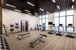 Een sportschool met loopbanden, elliptische trainers, gewichten en fitnessballen.