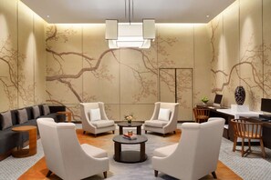 Een moderne woonkamer met een bank, twee fauteuils, een salontafel en een bureau met een computer.