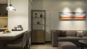 A modern living room with a sofa, ottoman, and a dining area with chairs and a table.