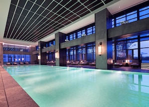 A large indoor swimming pool with multiple lounge areas and large windows. - HUALUXE Wuhu by IHG (Wuhu)