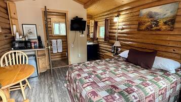 A cozy cabin room with a bed, a desk, a chair, and a television.
