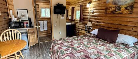 Une chambre confortable dans un chalet, avec un lit, un bureau, une chaise et un téléviseur.
