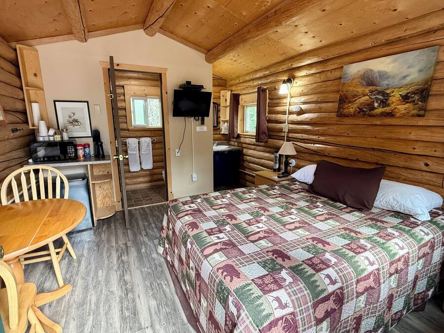 A cozy cabin room with a bed, a desk, a chair, and a television.