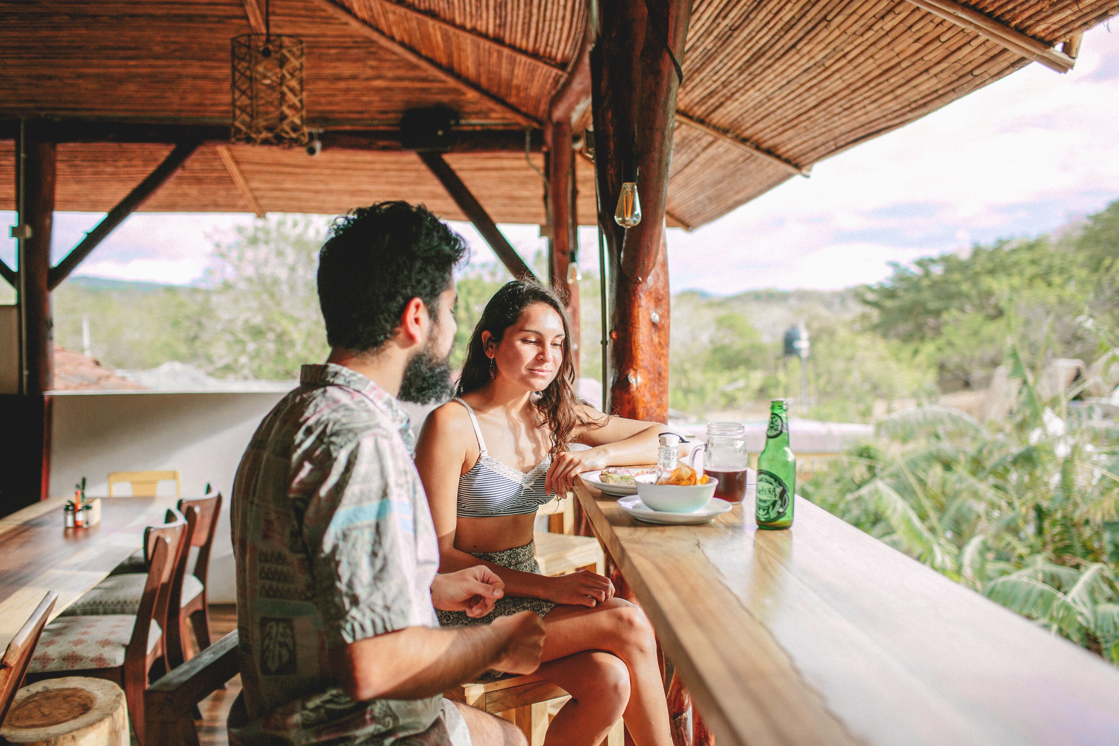 Una pareja cenando en una mesa de madera con vistas a la vegetación.