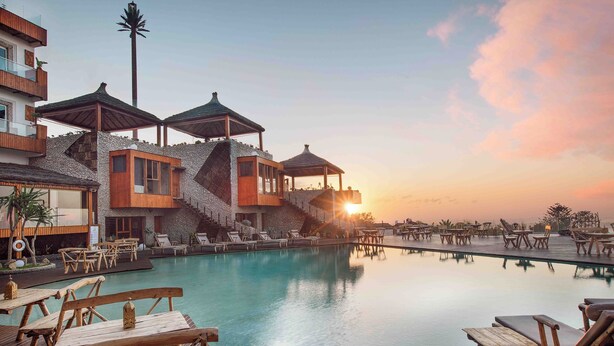 Ein Resort mit Schwimmbad, Holzterrasse und Liegestühlen.