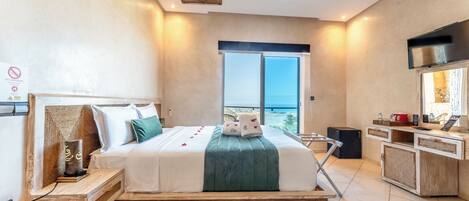 Una habitación de hotel moderna con una cama grande, un televisor, un minibar y un balcón con vistas.
