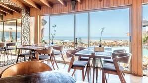Ein Restaurant mit Holzvertäfelungen und großen Fenstern mit Blick auf einen Strand.