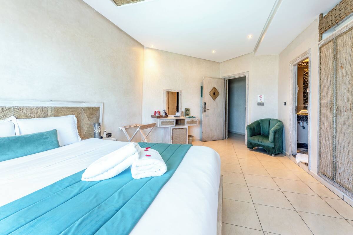A hotel room with a bed, a desk, a chair, and a wardrobe.