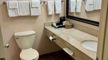 Une salle de bain équipée de toilettes, d’un lavabo et de plusieurs serviettes suspendues sur un porte-serviettes.