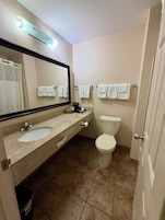 Un baño con lavamanos, espejo, inodoro y toallas.
